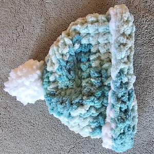 Puede incluir: Un gorro de punto azul y blanco con un pompón blanco esponjoso en la parte superior.