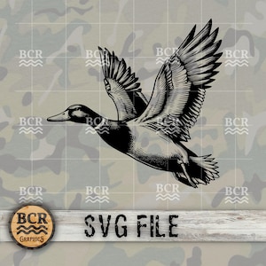 May include: Black and white illustration of a duck in flight. The duck is flying with its wings spread wide. The image is on a camouflage background with the text "BCR Graphics" in a circle at the bottom.