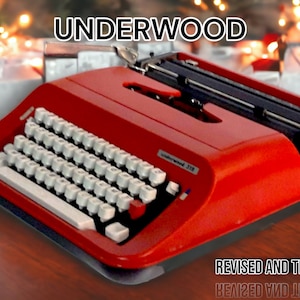 Puede incluir: Una máquina de escribir vintage Underwood 21B roja con una palanca de retorno de carro negra y teclas blancas. La máquina de escribir está sobre una superficie de madera con luces de Navidad y regalos envueltos en el fondo.