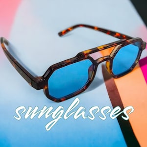 Può includere: Occhiali da sole tartaruga con lenti blu. Gli occhiali sono su uno sfondo colorato con la parola "sunglasses" scritta in bianco.