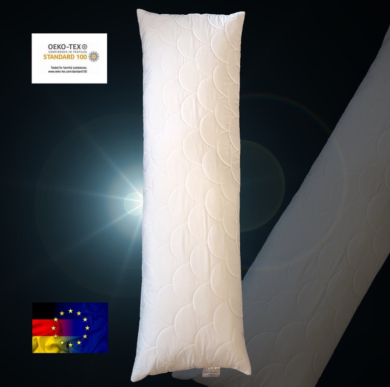 May include: A long, white rectangular body pillow featuring a quilted pattern of overlapping circular arcs. The pillow includes a small white tag at the bottom and a visible Oeko-Tex Standard 100 certification label in the upper left corner.