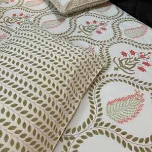 May include: White bed linen set featuring a floral design in red, green, and beige. The set includes a pillow and a fitted sheet. The pillow has a beige border. The fitted sheet has a repeating floral pattern.