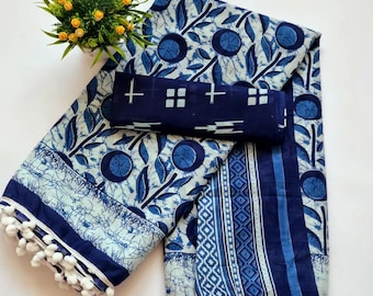 Può includere: Un sari di cotone blu e bianco con una stampa floreale e un bordo di pon pon bianchi. Il sari è piegato a metà e ha un pezzo di blusa abbinato.