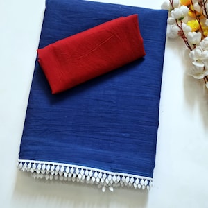 May include: A folded, deep blue fabric with a red fabric on top. The blue fabric has a white, leaf-shaped trim along the bottom edge. White flowers with yellow centers are in the background.
