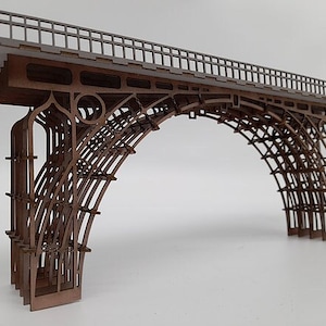 Può includere: Un modello dettagliato di un ponte in legno. Il ponte ha un design a traliccio ed è dipinto di marrone. Il modello è una replica in miniatura di un ponte reale.