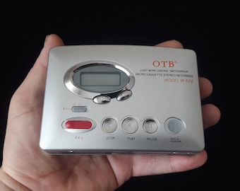 May include: Silver micro cassette stereo recorder with a digital display and buttons for play, pause, stop, record, and hold. The device is labeled "OTB Light Work Control Switchgroup Micro Cassette Stereo Recorder Model W-528".