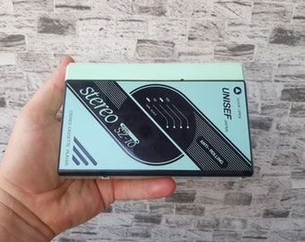 May include: A light green cassette player with black accents. The player has the text "stereo SZ-10 MODEL" and "STEREO CASSETTE PLAYER" on the front. The text "UNISEF JAPAN" and "ANTI-ROLLING" are also on the front of the player.