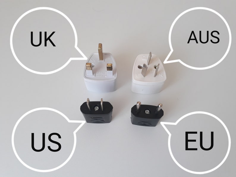 May include: Four different electrical plug adapters labeled UK, AUS, US, and EU. The UK and AUS adapters are white, while the US and EU adapters are black. Each adapter has a unique plug configuration.