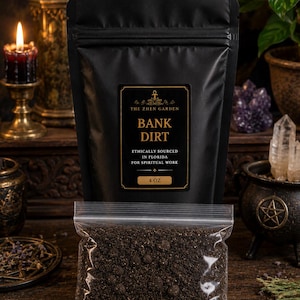 May include: A black matte pouch labelled The Zhen Garden Bank Dirt Ethically Sourced In Florida For Spiritual Work 4 OZ, accompanied by a clear plastic bag filled with dark brown soil, featuring a granular texture and small clumps throughout.