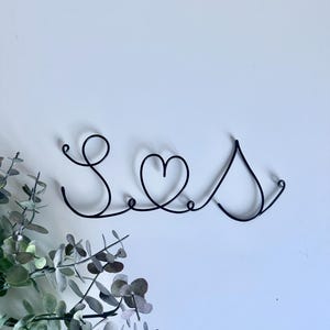 May include: A black wire sculpture of the word "Love" with a heart in the middle.