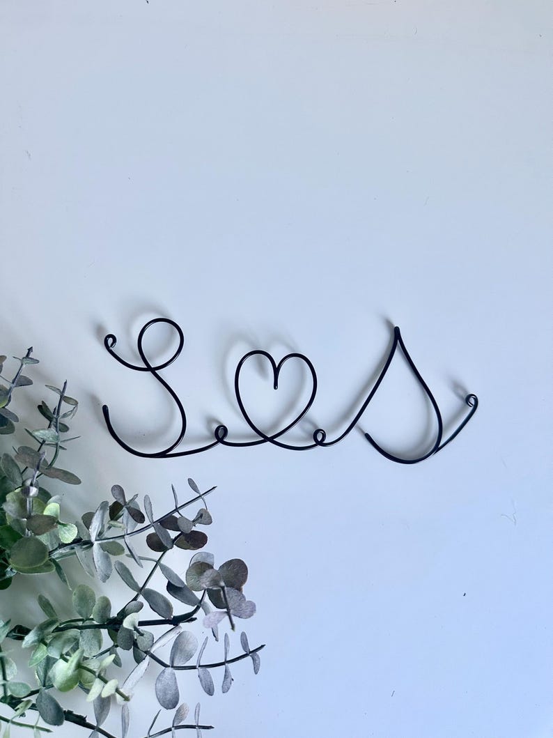 May include: A black wire sculpture of the word "Love" with a heart in the middle.