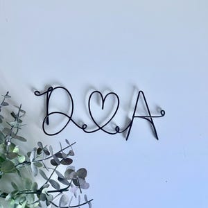 May include: Black wire art sculpture of the letters D and A with a heart symbol between them.