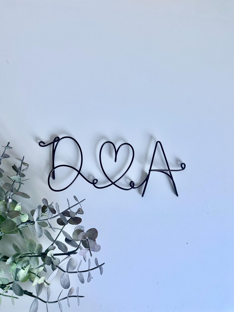 May include: Black wire art sculpture of the letters D and A with a heart symbol between them.