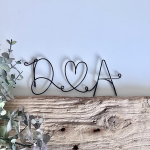 May include: Black wire sculpture of the letters D & A with a heart in between.
