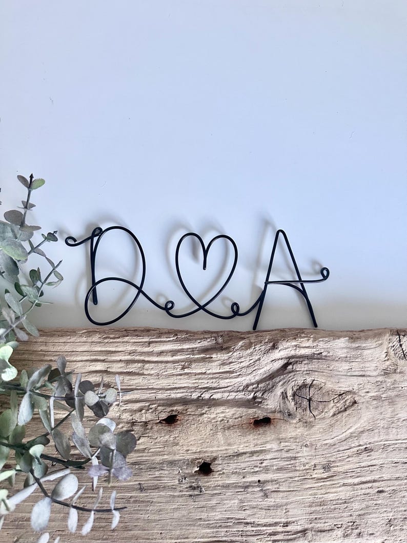 May include: Black wire sculpture of the letters D & A with a heart in between.