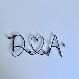 May include: A black wire sculpture of the letters "D & A" with a heart in between the letters.