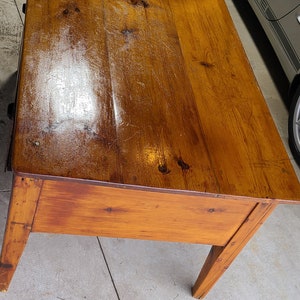 Könnte beinhalten: Ein Holztisch mit hellbrauner Oberfläche. Der Tisch hat eine rechteckige Tischplatte und vier Beine. Der Tisch steht in einer Garage.