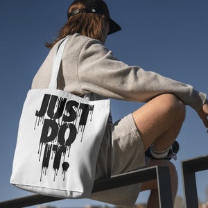 May include: A white tote bag with black dripping text that reads "JUST DO IT."