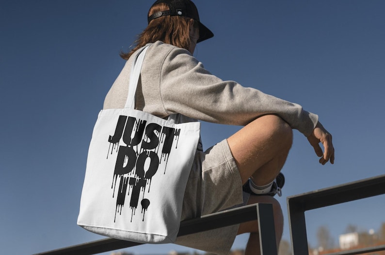 May include: A white tote bag with black dripping text that reads "JUST DO IT."