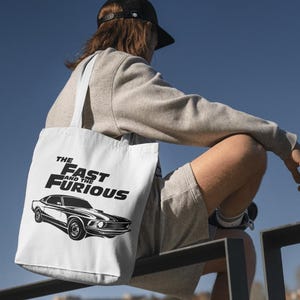 Może przedstawiać: Biała torba typu tote z czarno-białym nadrukiem samochodu i tekstem "The Fast and the Furious".