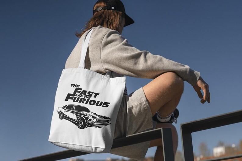 Może przedstawiać: Biała torba typu tote z czarno-białym nadrukiem samochodu i tekstem "The Fast and the Furious".
