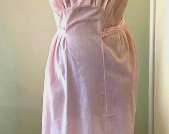 Könnte beinhalten: Ein hellrosa ärmelloses Kleid mit rundem Ausschnitt und weißem Spitzenkragen, einer durchgehenden Knopfleiste mit drei sichtbaren Knöpfen sowie einer taillierten Passform, die in einen geraden, bodenlangen Rock übergeht.