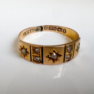 May include: A gold ring with star and square designs, set with small gemstones. The ring has a polished finish and is stamped with markings including "9 375". The ring is likely vintage or antique.