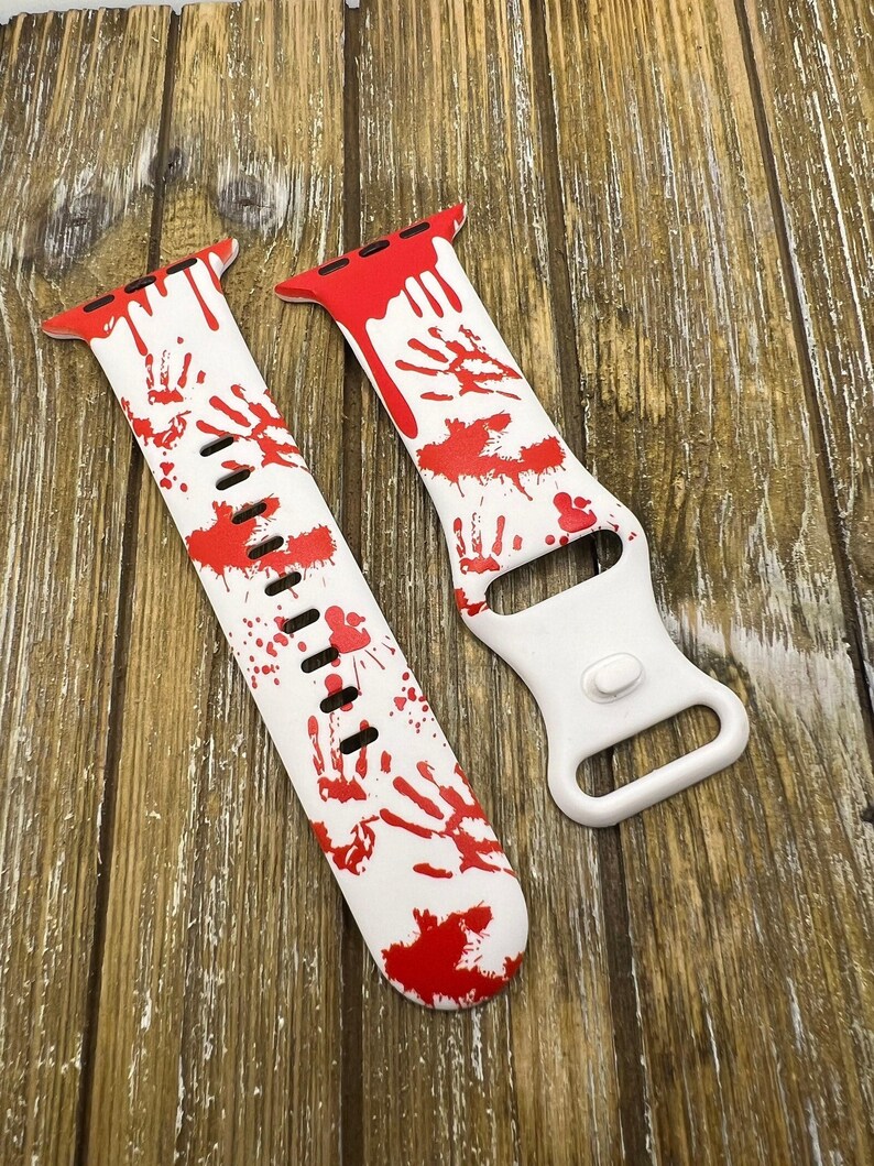 Puede incluir: Correa de reloj blanca con dise&ntilde;o de huellas de manos rojas. La correa presenta huellas de manos y salpicaduras rojas, creando una est&eacute;tica espeluznante con tem&aacute;tica de Halloween. La correa est&aacute; hecha de un material flexible.