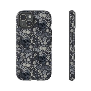 May include: A black phone case featuring a floral pattern and skull design. The case has a raised camera bump and cutouts for the phone's buttons.