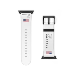 May include: White Apple Watch band with black hardware. The band features the word "FREEDOM" and an American flag design. The text "Charlie Kirk" is also visible on the band.