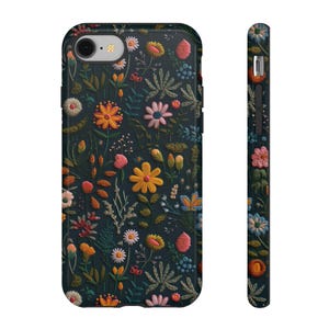 May include: A phone case with a dark background and a colorful floral pattern. The design features various flowers in shades of orange, pink, yellow, and white, along with green leaves. The case is shown from the front and side.