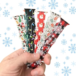 May include: A set of six colourful Christmas-themed watch bands. The bands are made of silicone and feature various holiday designs, including snowflakes, lights, and Santa Claus.