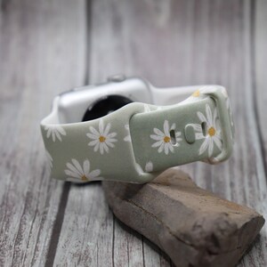 Puede incluir: Una correa de reloj de silicona verde y blanca con estampado de margaritas. La correa est&aacute; dise&ntilde;ada para Apple Watch.