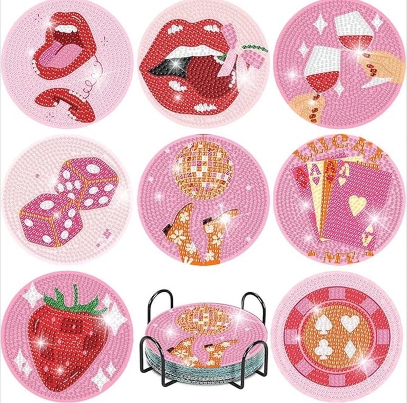 May include: Set of nine pink coasters with various designs, including red lips, dice, playing cards, a strawberry, and a disco ball. The coasters are round and have a textured appearance. A black metal stand holds the coasters.