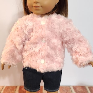 May include: A pink faux fur jacket with white buttons. The jacket is being worn by a doll with brown hair and brown eyes.