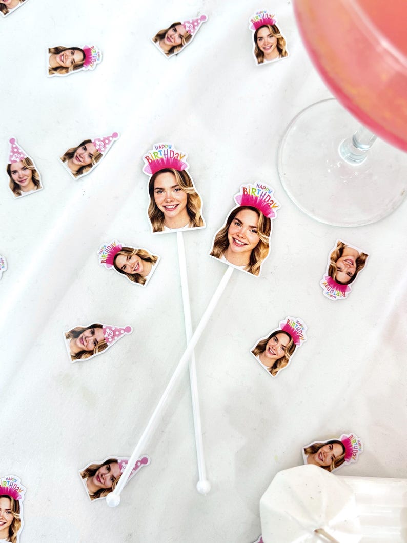 K&ouml;nnte beinhalten: Wei&szlig;e Cocktailr&uuml;hrer mit dem Gesicht einer l&auml;chelnden Frau und dem Schriftzug "Happy Birthday" auf einem rosa Kr&ouml;nchen. &Auml;hnliche Bilder der Frau mit Partyhut sind verstreut. Ein Glas mit einem rosa Getr&auml;nk ist zu sehen.