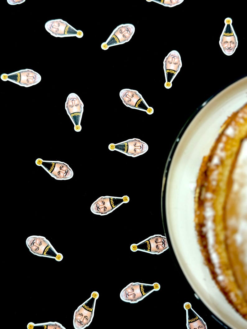 May include: A black background scattered with small stickers featuring a man's face wearing a party hat with the word "retired" on it. A partially visible plate of cake is in the right corner.