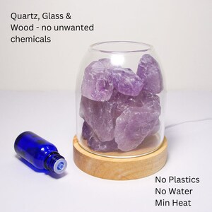 K&ouml;nnte beinhalten: Ein Glasdiffusor mit Holzsockel und Amethystkristallen im Inneren. Der Diffusor ist beleuchtet und hat eine blaue &auml;therische &Ouml;l-Flasche daneben. Der Text "Quartz, Glass & Wood - no unwanted chemicals" befindet sich oben im Bild. Der Text "No Plastics No Water Min Heat" befindet sich unten im Bild.