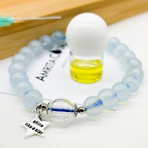 May include: A light blue beaded bracelet with a clear crystal charm and a silver star charm that says "shine like a star". The bracelet is accompanied by a small bottle of essential oil.