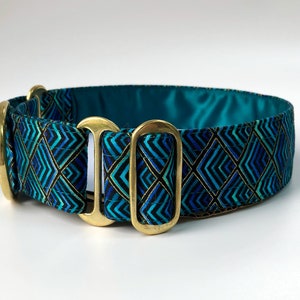 Pu&ograve; includere: Un collare per cani blu turchese con un motivo geometrico in tonalit&agrave; di blu, verde e oro. Il collare ha due anelli a D in ottone.