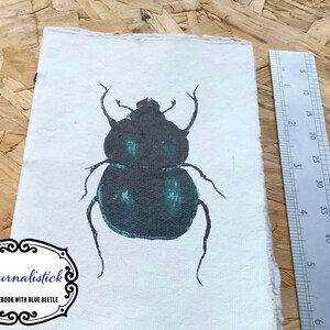 Bellissimo diario di carta fatto a mano in formato A6 con illustrazione dello scarabeo blu sulla copertina. Scrapbooking, junk journaling, bullet journaling, schizzi.