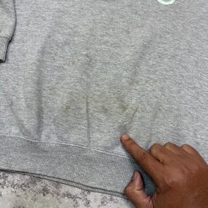 May include: A gray sweatshirt with the embroidered text "cute things" in pastel colors. The sweatshirt has a ribbed hem and cuffs. There are some stains on the front of the sweatshirt.