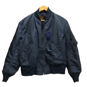 Peut inclure: Un blouson aviateur bleu foncé avec une fermeture éclair frontale, un col, des poignets et un ourlet côtelés. Le vêtement présente deux poches latérales à boutons-pression, une poche utilitaire sur la manche gauche et un écusson rectangulaire.