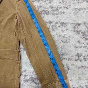 Puede incluir: Blazer de pana color beige con solapa de muesca y dos bolsillos delanteros. La longitud de la manga es de aproximadamente 63.5 cm, medida con una cinta m&eacute;trica azul. Dise&ntilde;o cl&aacute;sico y entallado.