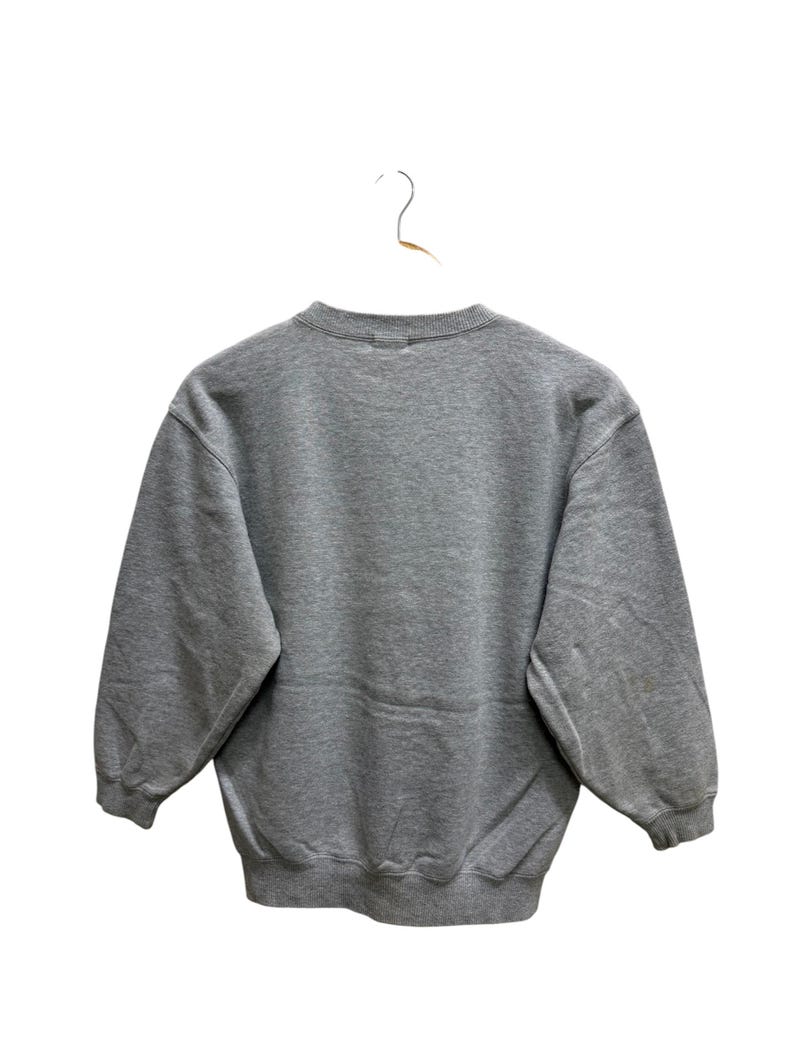 May include: A heather gray sweatshirt with a crew neck and long sleeves, hanging on a white hanger. The back of the sweatshirt is visible, showcasing its simple, classic design. The fabric appears soft and comfortable.