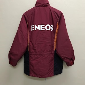 May include: A maroon jacket with orange and black accents. The jacket has a high collar and a zipper closure. The back of the jacket has the word "ENEOS" printed in white.