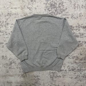 May include: A heather gray sweatshirt with a crew neck and long sleeves. The garment is made of a soft, comfortable material. The sweatshirt is a casual, everyday wear item.