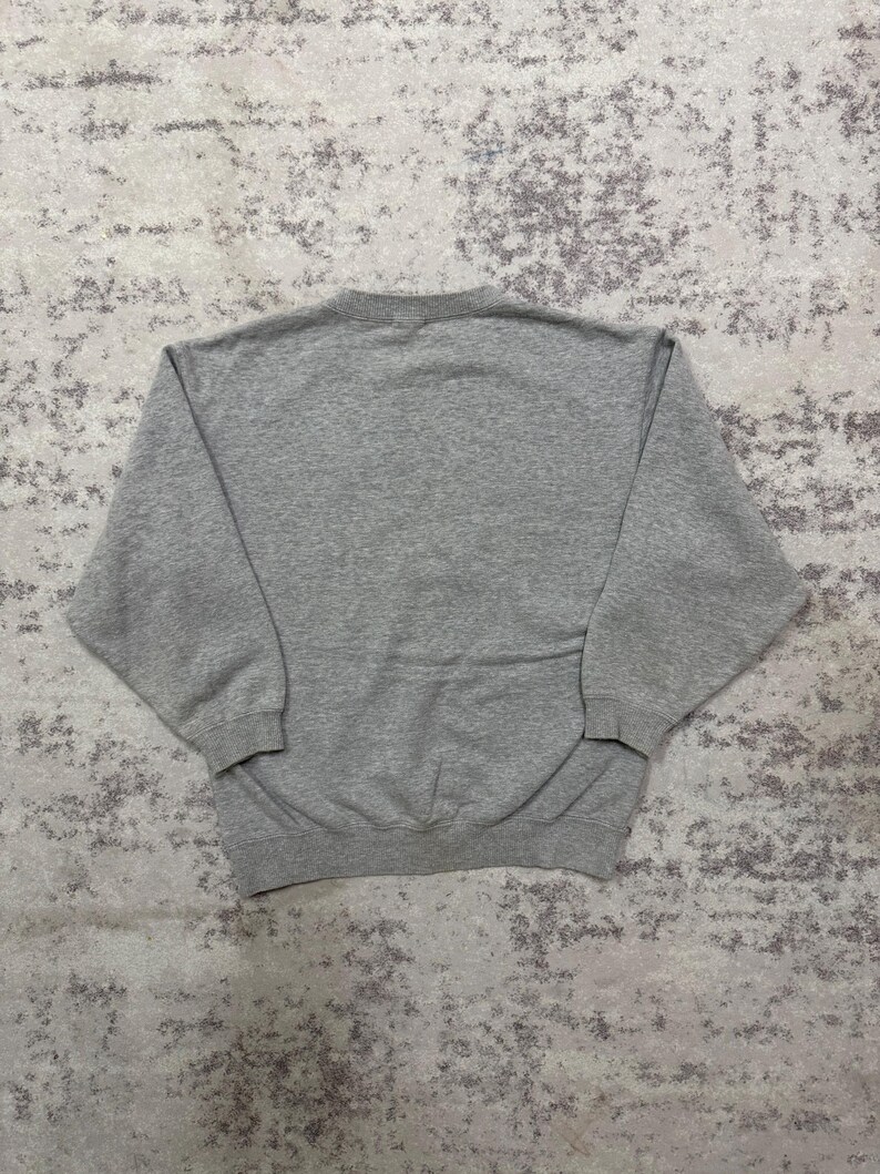 May include: A heather gray sweatshirt with a crew neck and long sleeves. The garment is made of a soft, comfortable material. The sweatshirt is a casual, everyday wear item.
