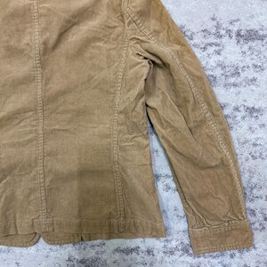 Puede incluir: Un blazer de pana color beige con un dise&ntilde;o cl&aacute;sico. La chaqueta presenta solapas con muescas, cierre de dos botones y un corte entallado. La tela de pana tiene una textura acanalada. Se ve la manga.