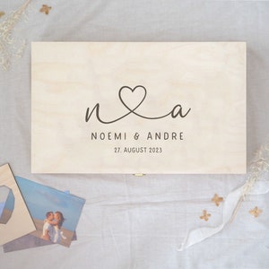 Könnte beinhalten: Eine Holzkiste mit einem Herzdesign und dem Text "n&a Noemi & Andre 27. August 2023" auf dem Deckel.